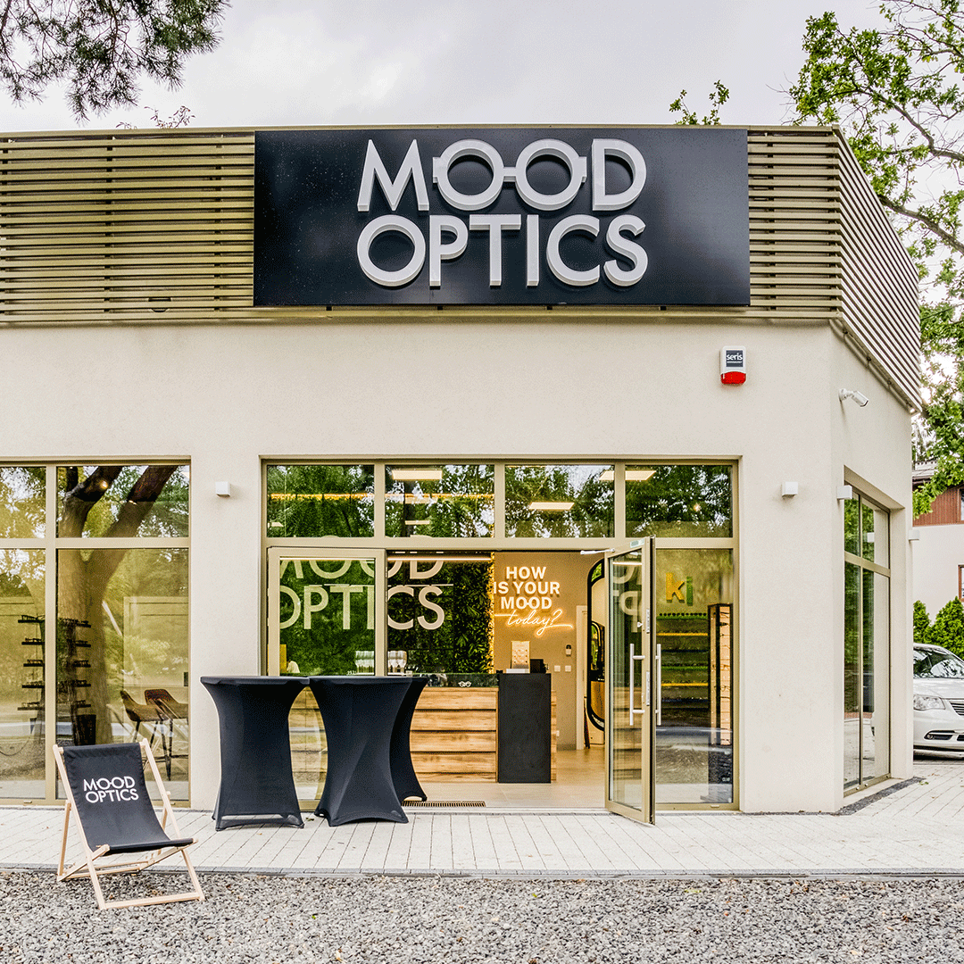 Front sklepu z wyraźnym szyldem "Mood Optics", zachęcający do odwiedzin i oferujący luksusowe okulary.
